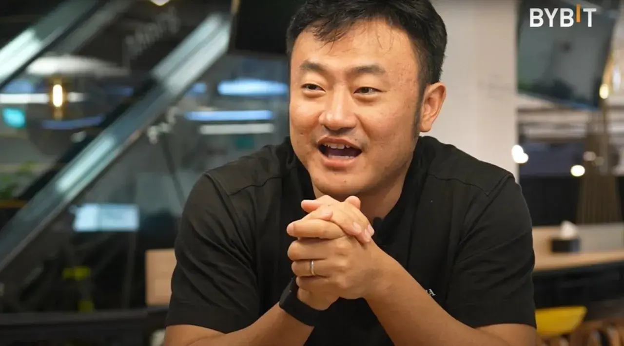 Ben Zhou, w czarnej koszulce, z dłońmi złożonymi na piersi, opowiada o przyszłości kryptowalut.