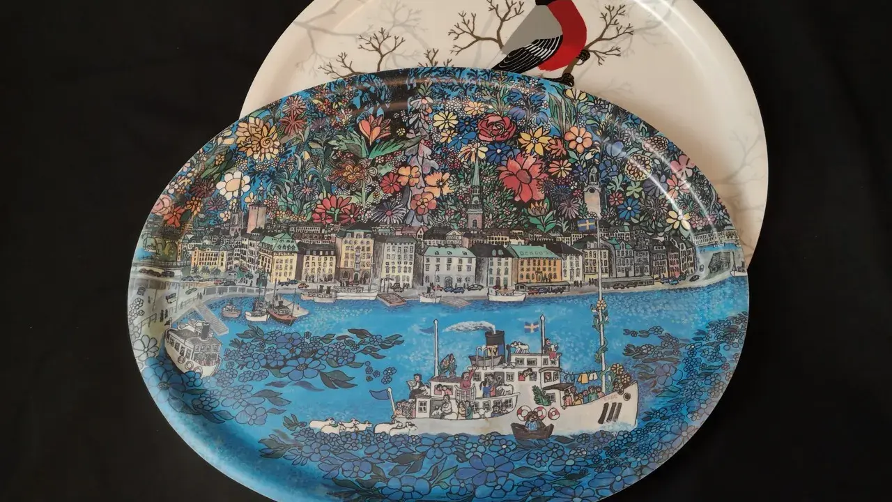 Två brickor, en med en detaljerad stadsvy och fartyg, den andra med en domherre och träd. En fin bengt elde bricka.