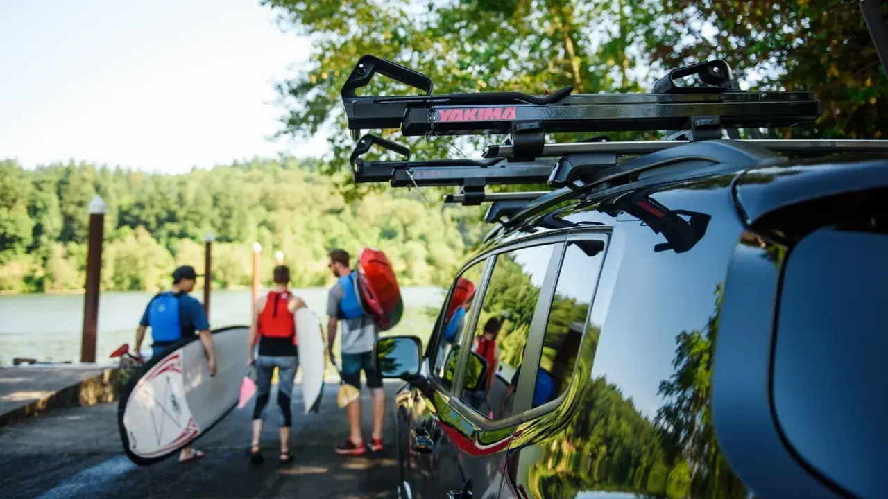 Ludzie przygotowują się do wodnej przygody, transport kajaka i desek SUP do jeziora.