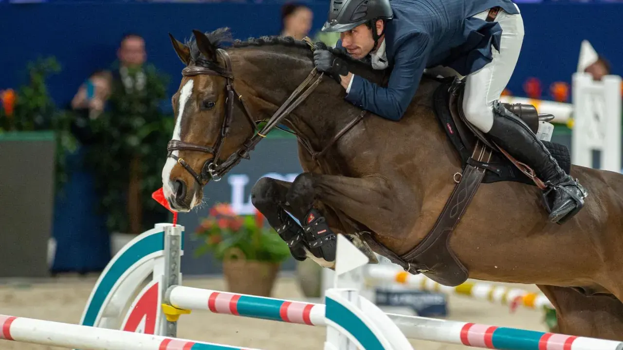 Reiter und Pferd im Sprung über ein Hindernis. Die Haltung des Reiters, die Anspannung des Pferdes und die elektrischen Sporen deuten auf einen spannenden Wettkampf hin.