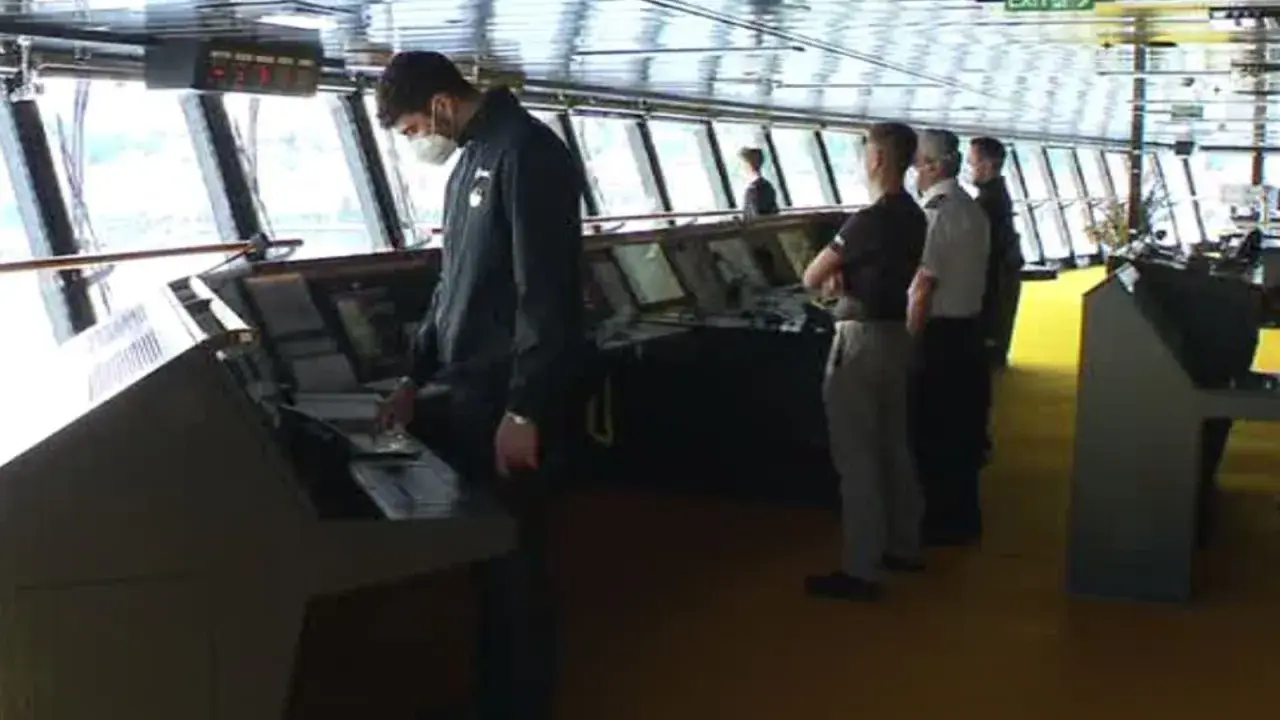 Equipaggio sulla plancia nave da crociera, con strumenti di navigazione e grandi finestre.