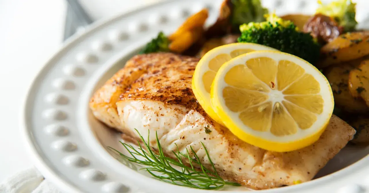 Pieczony halibut z cytryną i koperkiem, podany z pieczonymi ziemniakami i brokułami. Zdrowe danie, które nie musi mieć wielu halibut kcal.
