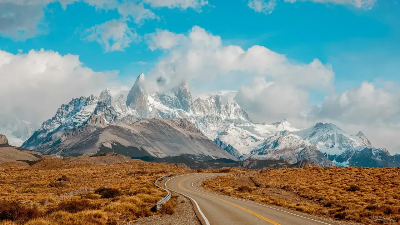 Droga wije się przez trawiastą równinę w kierunku majestatycznych, ośnieżonych szczytów Patagonii. Idealne miejsce dla marki Patagonia.