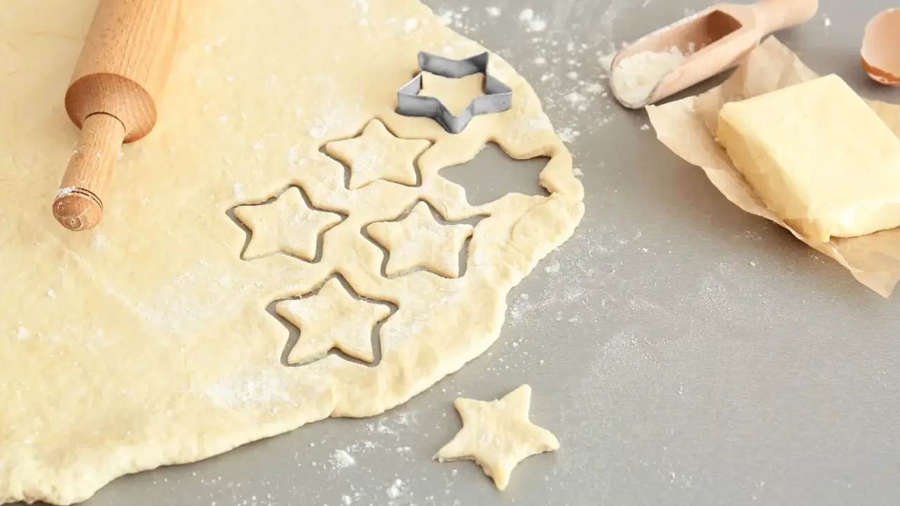 Plätzchenteig zu krümelig? Sterne werden ausgestochen. Teig, Nudelholz, Butter und Mehl sind bereit für leckere Kekse.