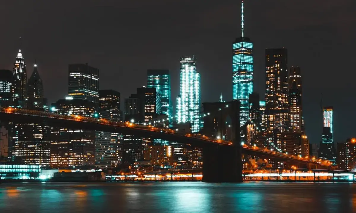 Il Ponte di Brooklyn illumina la **new york city vita notturna**, con grattacieli scintillanti che si riflettono sull'acqua scura.
