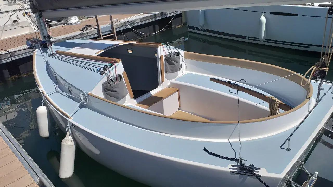 Un voilier Pabouk 700 bleu clair et blanc, prêt à naviguer, amarré à quai.