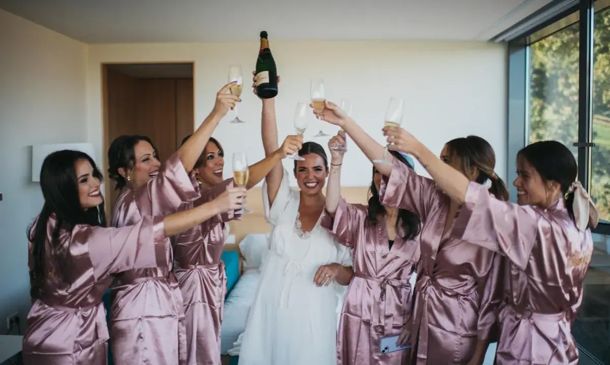 Novia y damas de honor brindan con champán, ¡ideas para despedidas llenas de alegría y celebración!