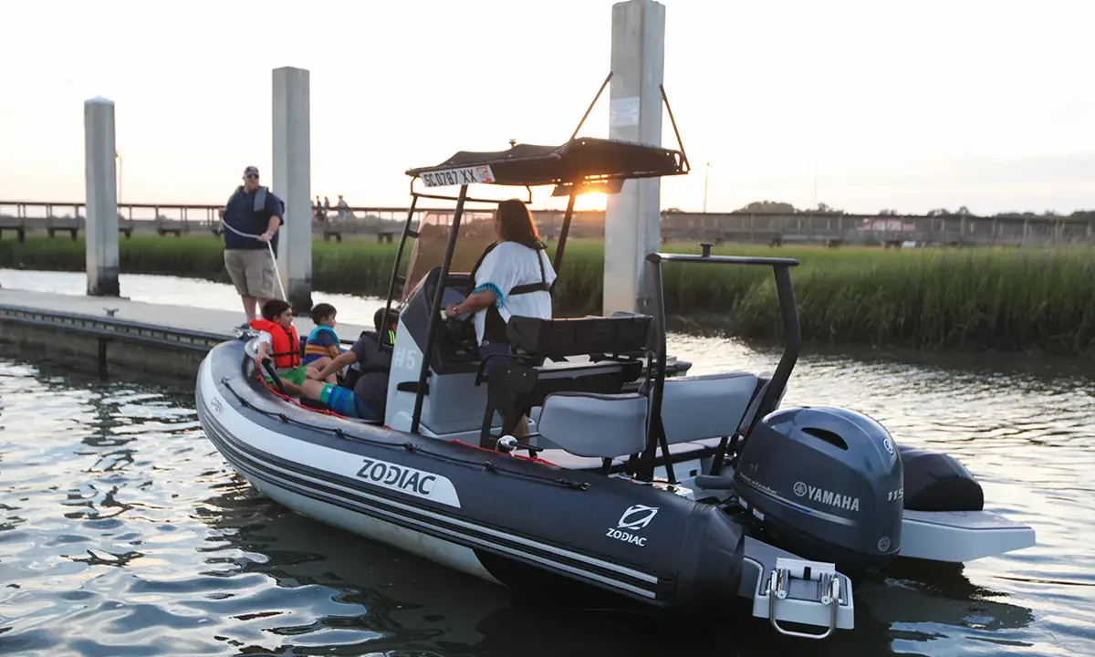 Bateau Zodiac prêt pour l'aventure, son hypalon garantissant une longue durée de vie. Famille à bord, profitant du coucher de soleil.