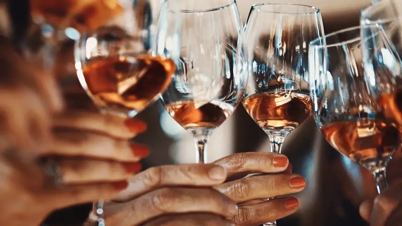 Hände halten Gläser mit Roséwein. Ein Genuss ohne Sulfite, vegan und köstlich.