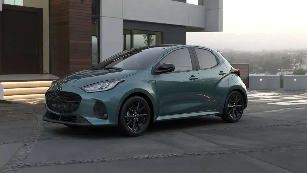 Elegancka, zielona Mazda 2 Hybrid stoi przed nowoczesnym domem.