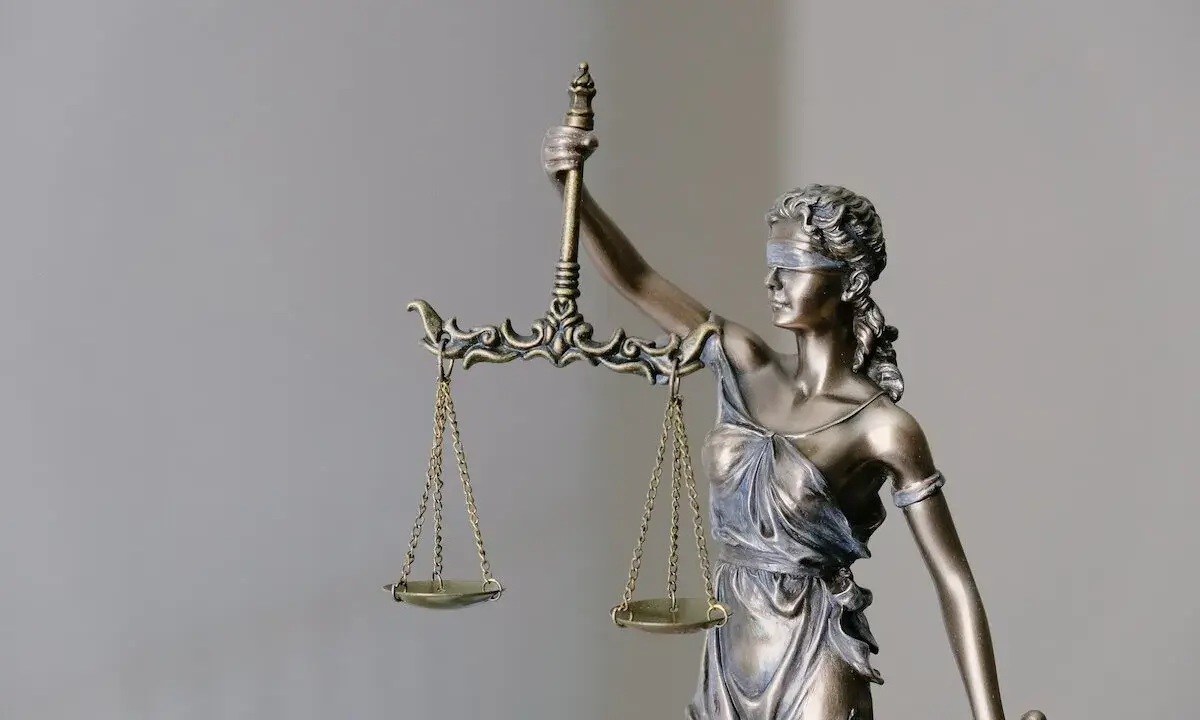 Figurka Temidy z wagą, symbol sprawiedliwości. Jej postawa sugeruje, że rozważa ona czynności przekraczające zwykły zarząd, szukając równowagi.
