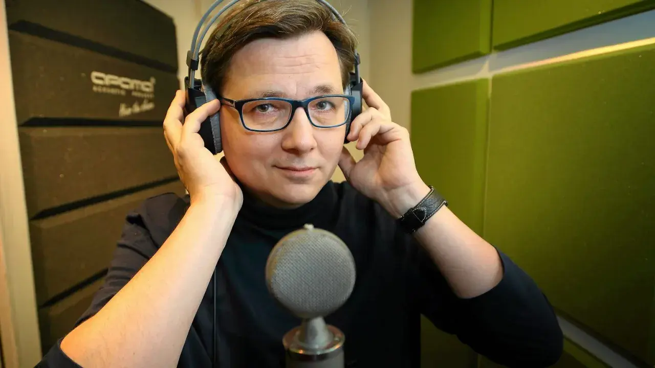 Mężczyzna w słuchawkach i okularach, gotowy do nagrania. Może to lektor porno, a może czyta bajki.