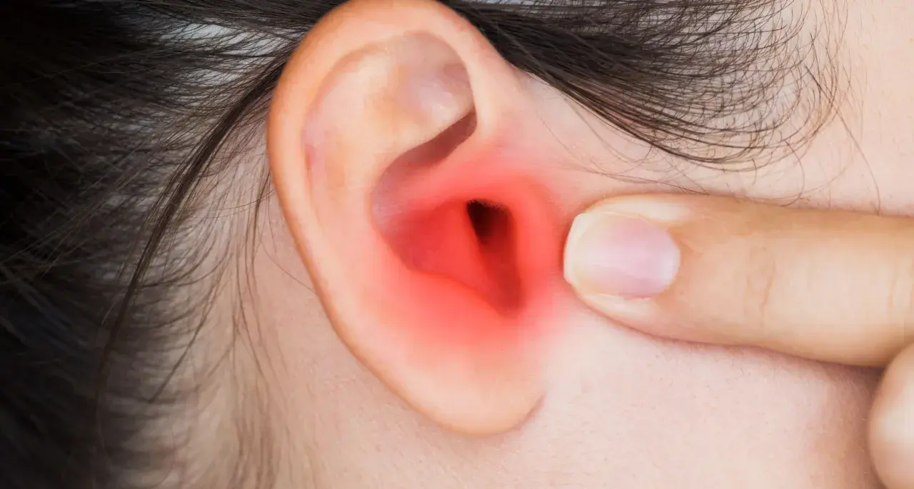 Dito un orecchio con un'area rossa che indica infiammazione, forse dovuta a pseudomonas aeruginosa orecchio.