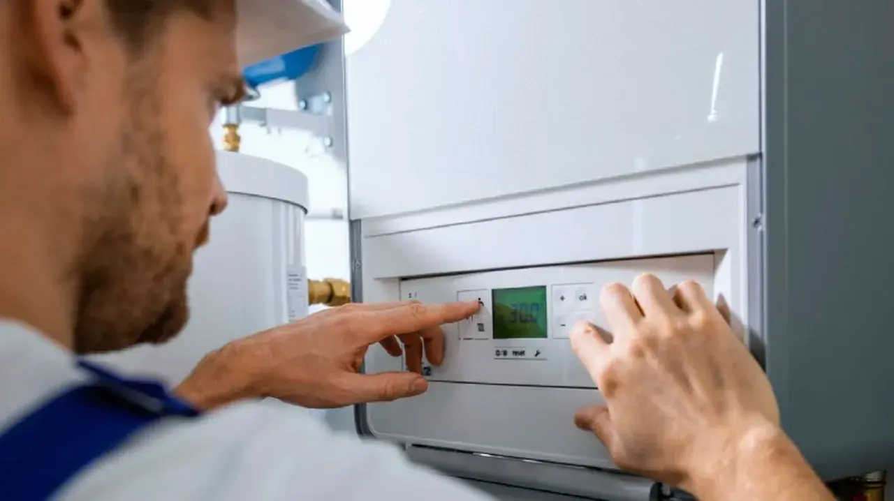 Técnico ajustando la temperatura en un calentador de gas butano. La pantalla digital muestra 30.0 grados.