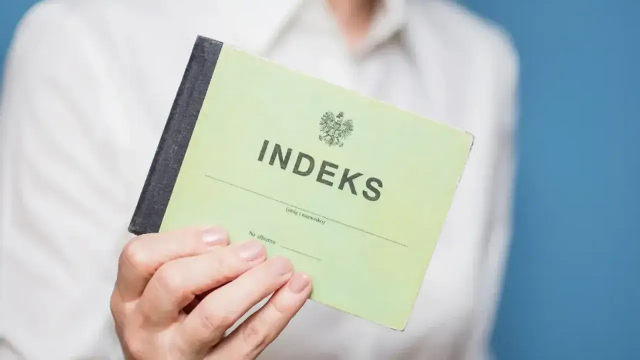 Zielony indeks, symbol studiów magisterskich w Łodzi, w dłoni studenta.