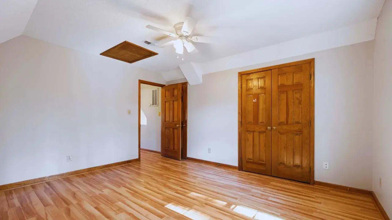Habitación con suelo de madera clara y puertas de madera oscura, creando un contraste cálido.
