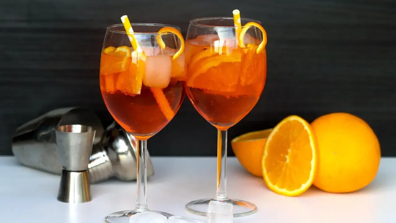 Deux Aperol Spritz prêts à déguster, avec des oranges fraîches et des glaçons. La recette parfaite pour un apéritif ensoleillé.