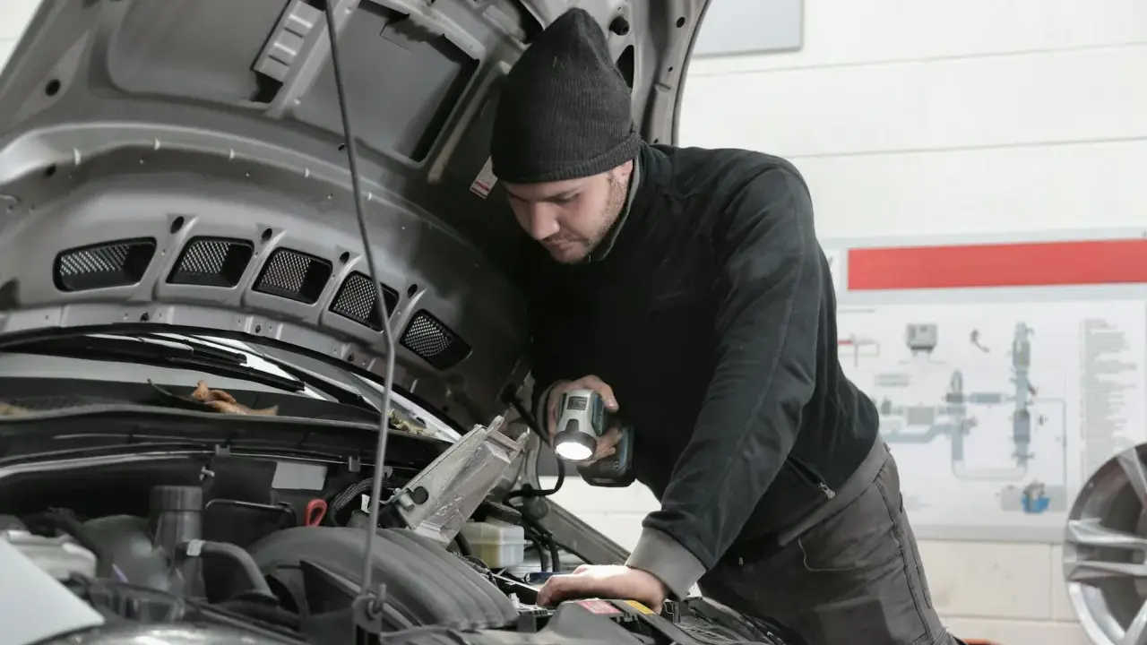 Mechanik z latarką bada silnik 1.6 TDI.