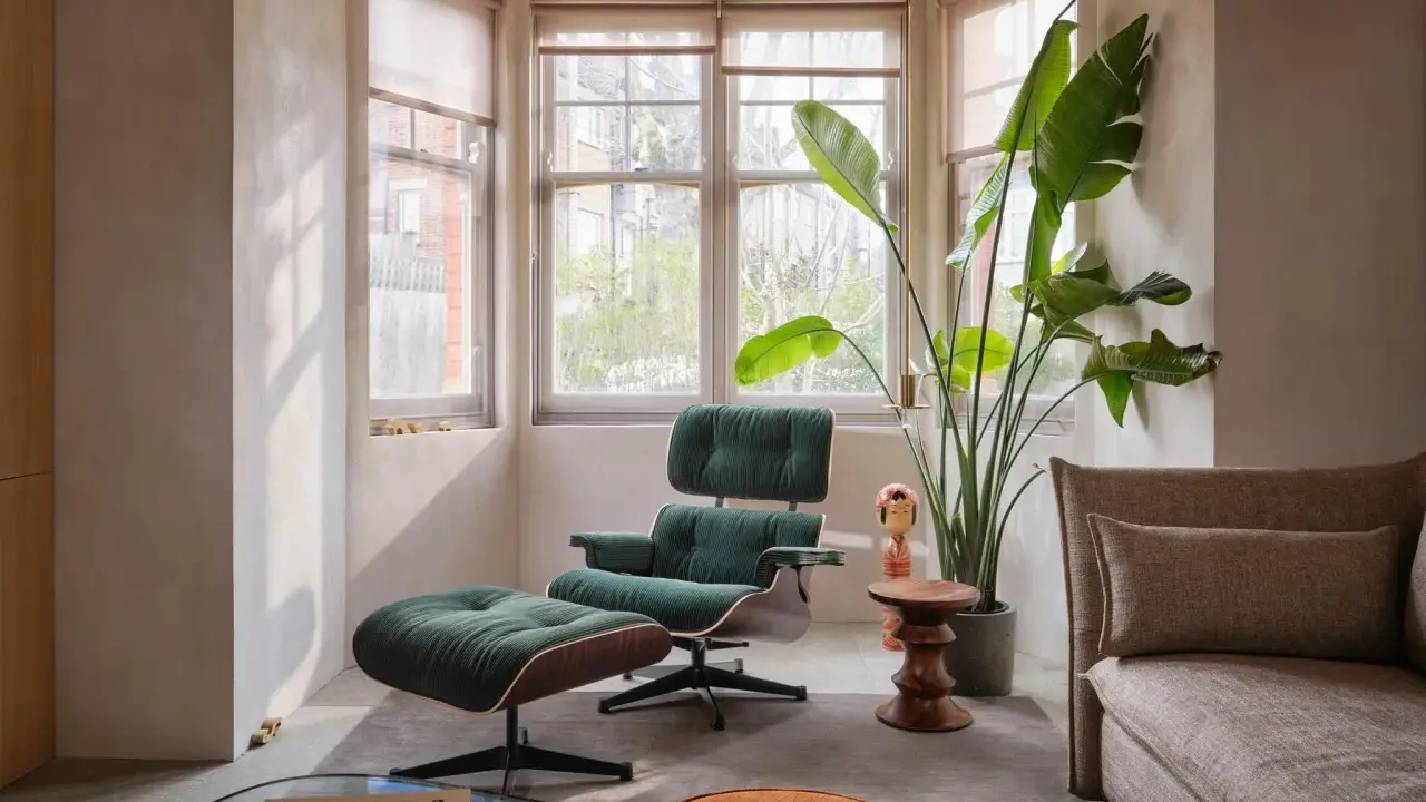 Gemütliche Ecke im **mid century style** mit einem grünen Cord-Sessel, Fußhocker, einer großen Pflanze und einem Sofa.