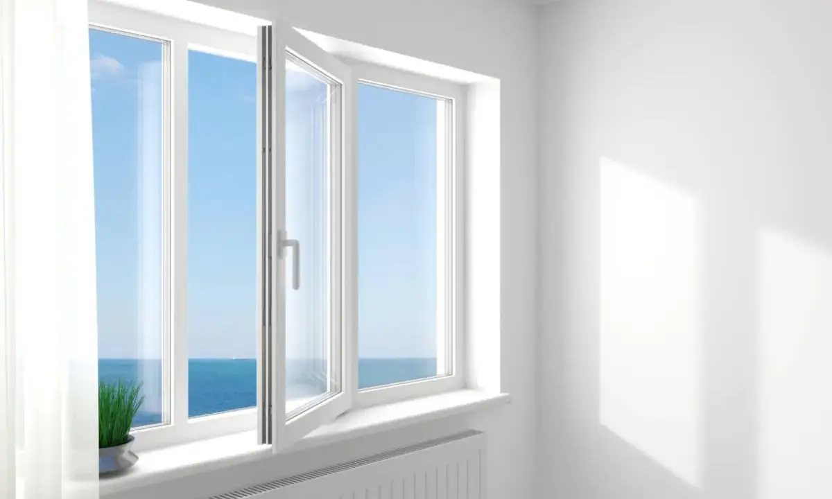 Ventana oscilobatiente de 2 hojas abierta, dejando entrar la brisa marina y la luz del sol.