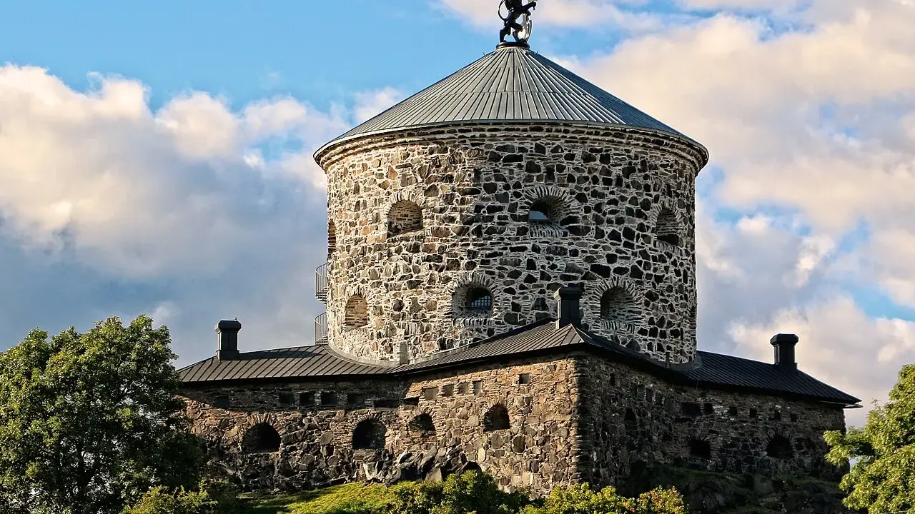 Skansen Lejonet, ett stendäckat torn med en gyllene lejonstaty på toppen, reser sig mot en molnig himmel.