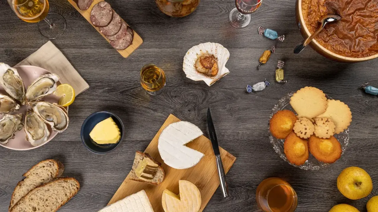 Un festin normand : huîtres, fromages, charcuterie, pommes et douceurs, accompagnés de verres de Calvados, pour savourer les spécialités locales.