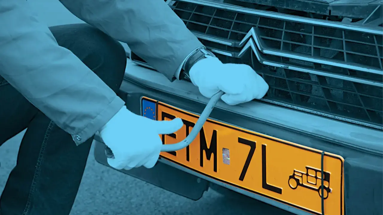 Ręce w białych rękawiczkach montują żółtą tablicę rejestracyjną z symbolem starego auta. Czy warto zarejestrować auto jako zabytek?