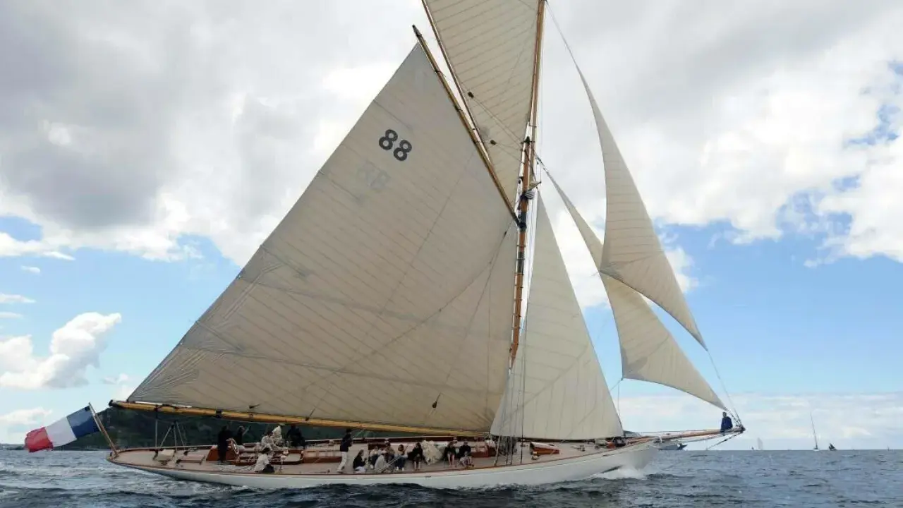 Le voilier "Moonbeam 4" navigue sur une mer agitée, ses voiles blanches gonflées par le vent.