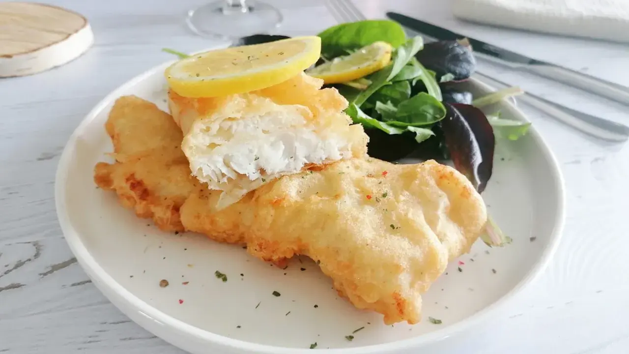 Poisson pané croustillant, servi avec une salade verte et des quartiers de citron. Un délice de fish and chips !