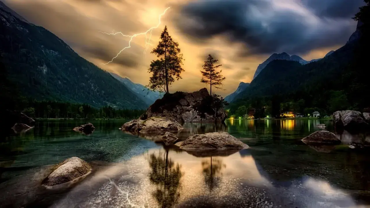 Dramatyczna burza nad jeziorem, błyskawica rozświetla niebo, a HDR w aparacie telefonu uchwycił piękno krajobrazu.