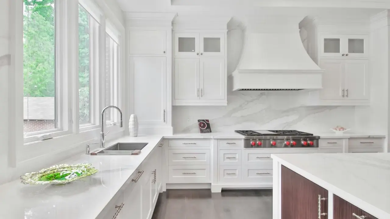 Cocina moderna y luminosa con muebles blancos, encimeras de cuarzo y electrodomésticos de acero inoxidable. Perfecta para pintar muebles de cocina y darles un nuevo aire.