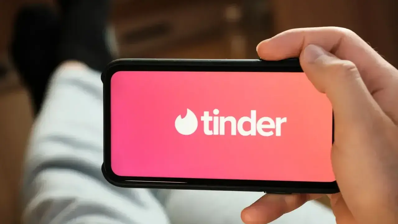 Dłoń trzyma smartfon z logo popularnych portali randkowych Tinder.