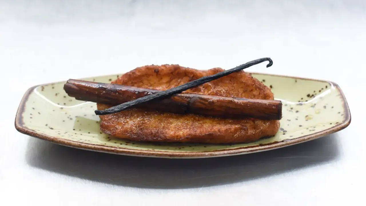 Torrijas de leche y canela, doradas y crujientes, con una rama de canela y vainilla. ¡Perfectas para aprender como hacer torrijas de leche y canela!