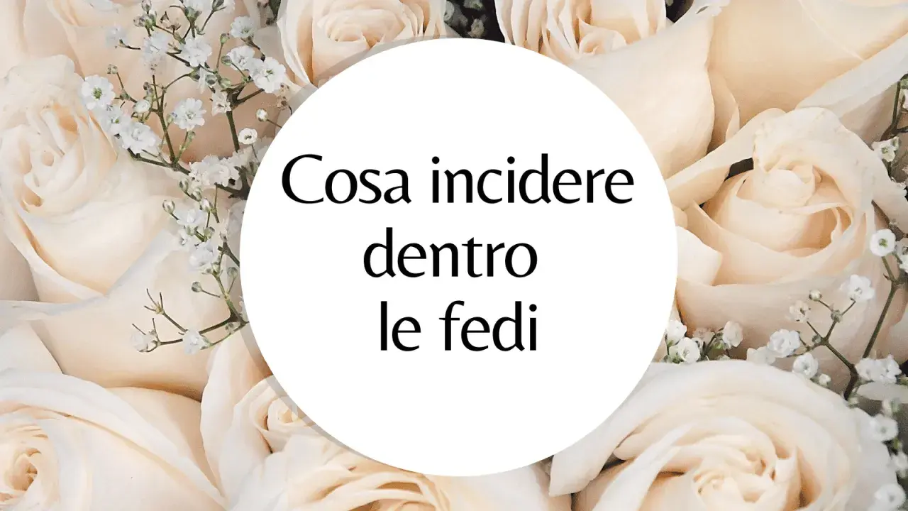 Un cerchio bianco su uno sfondo di rose color crema con la domanda: "Cosa incidere dentro le fedi?". Ispirazione per incisioni fedi nuziali frasi.