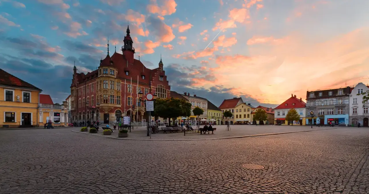 Rynek w Tarnowskich Górach o zachodzie słońca. Kolorowe chmury nad zabytkową zabudową i brukowanym placem, tworzą malownicze tarnowskie góry atrakcje.