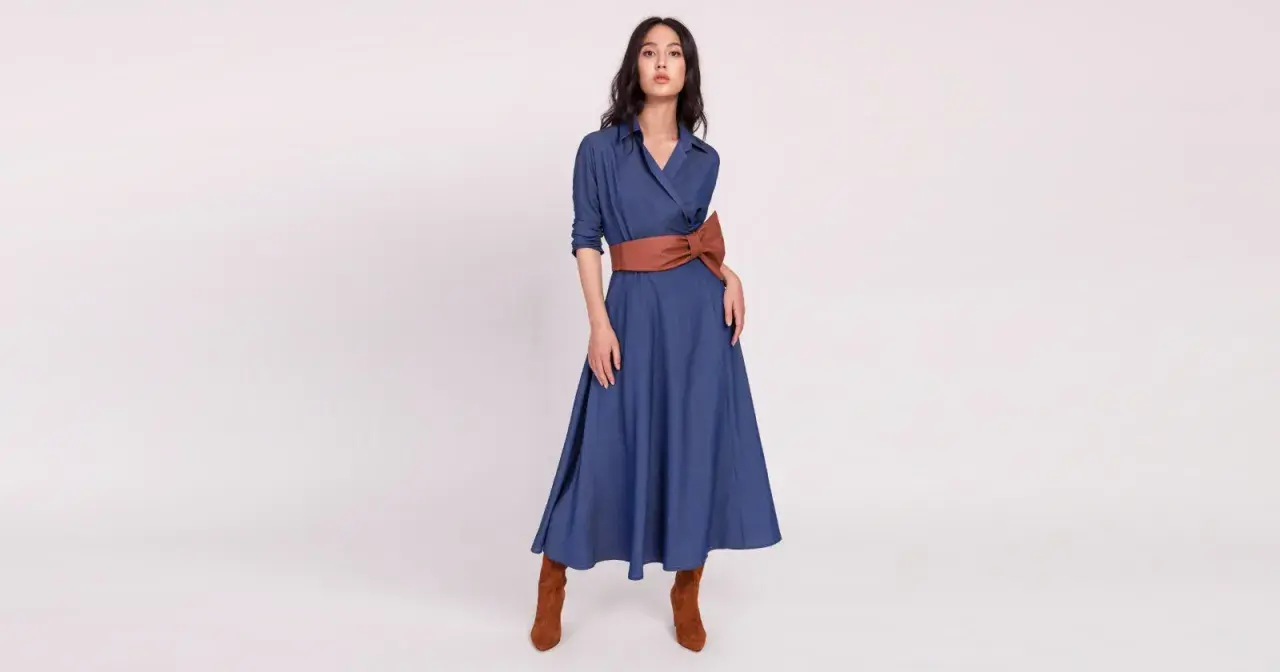 Modelka w niebieskiej sukience z brązowym pasem i botkami. Brązowy to kolor, jaki pasuje do niebieskiego, tworząc elegancką stylizację.