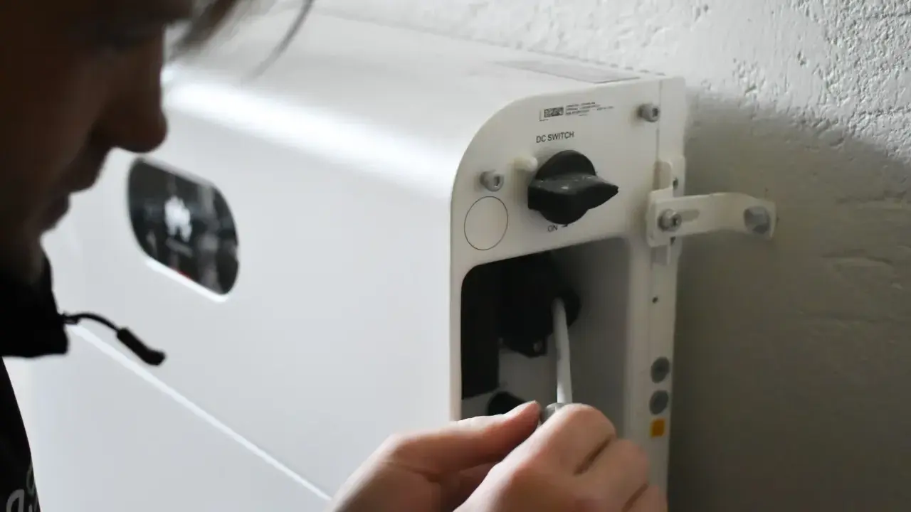 Person kopplar in en kabel i ett vitt system för att lagra solenergi batteri.