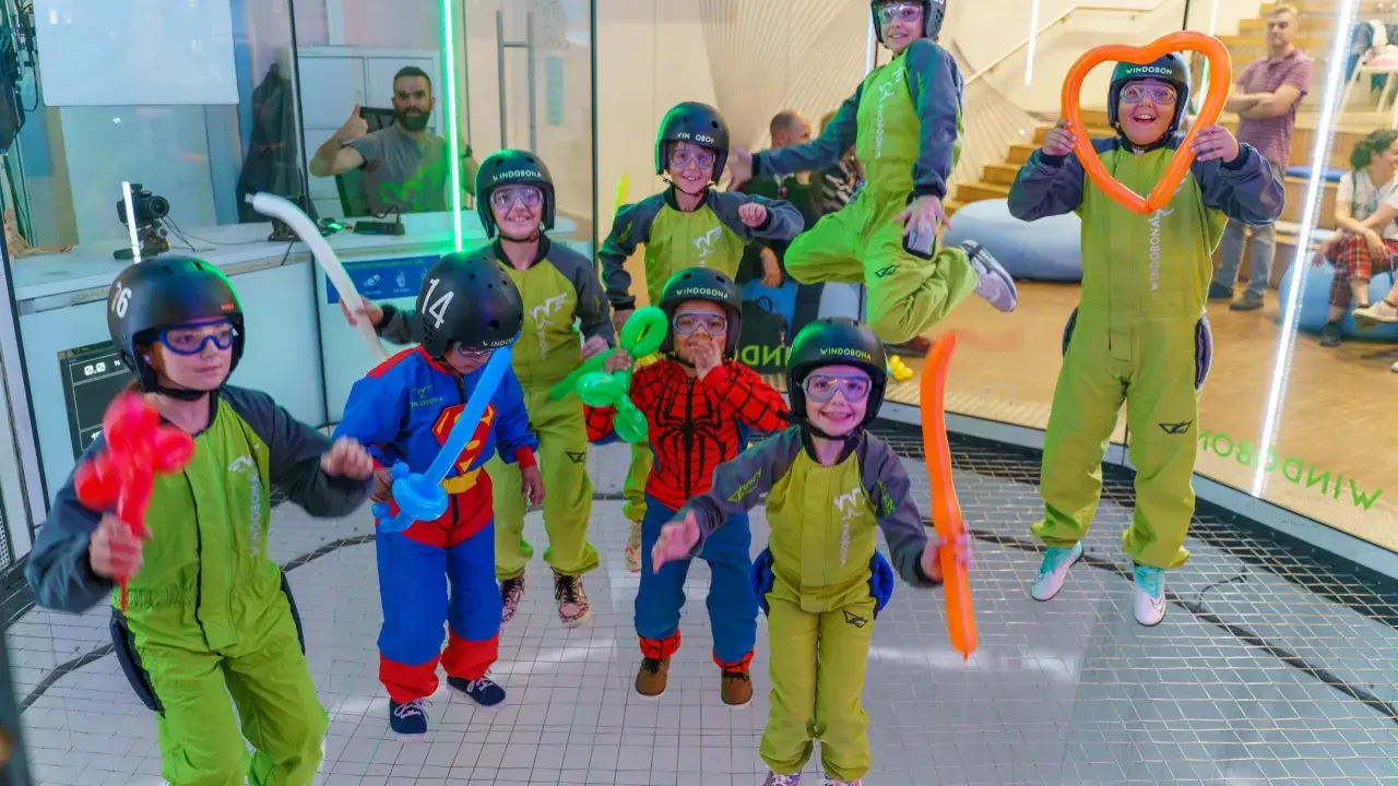 ¡Diversión volando en Madrid! Niños con trajes verdes y cascos disfrutan de la experiencia, algunos con globos. ¡Un fin de semana inolvidable!
