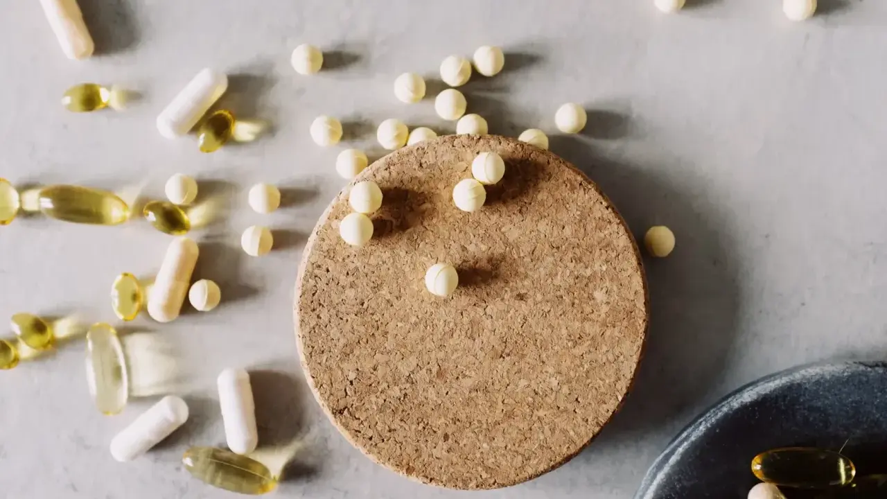 Kapseln und Pillen, darunter auch solche, die bei **Magnesium zum Abnehmen** helfen könnten, liegen verstreut auf hellem Untergrund.