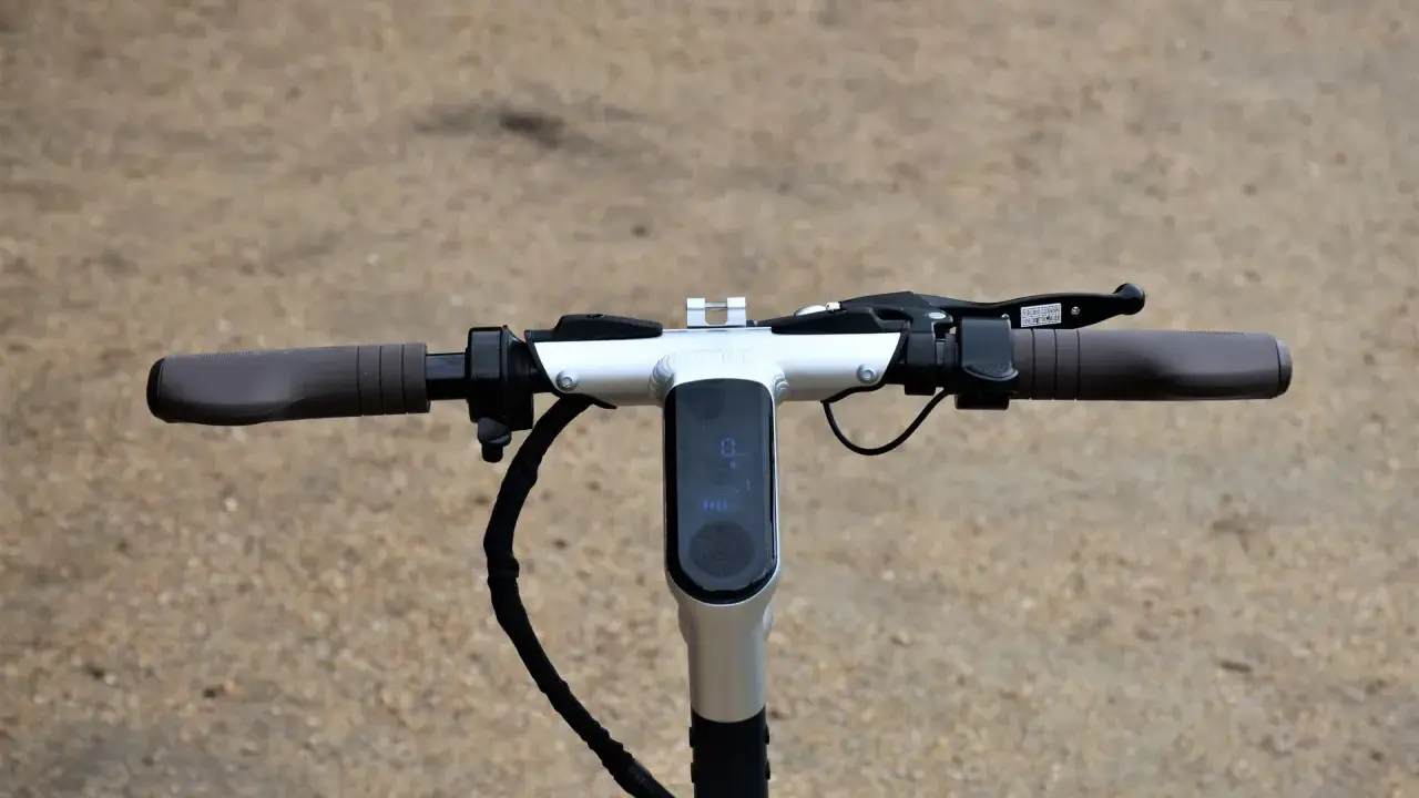 Guidon d'une trottinette électrique, avec écran digital affichant la vitesse et l'autonomie. La hauteur du guidon est idéale pour une conduite confortable.