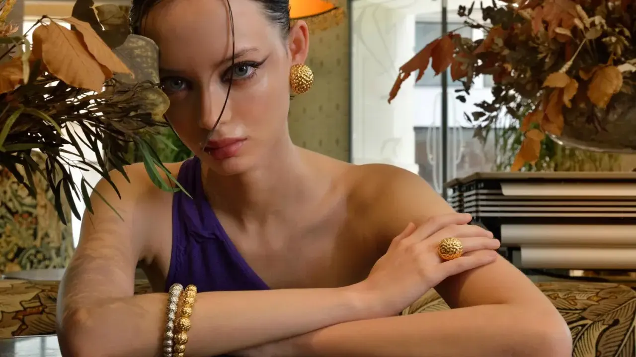 Modella con gioielli in oro e argento rosa, un bracciale, un anello e orecchini che sembrano quasi rovinarsi sotto la luce.