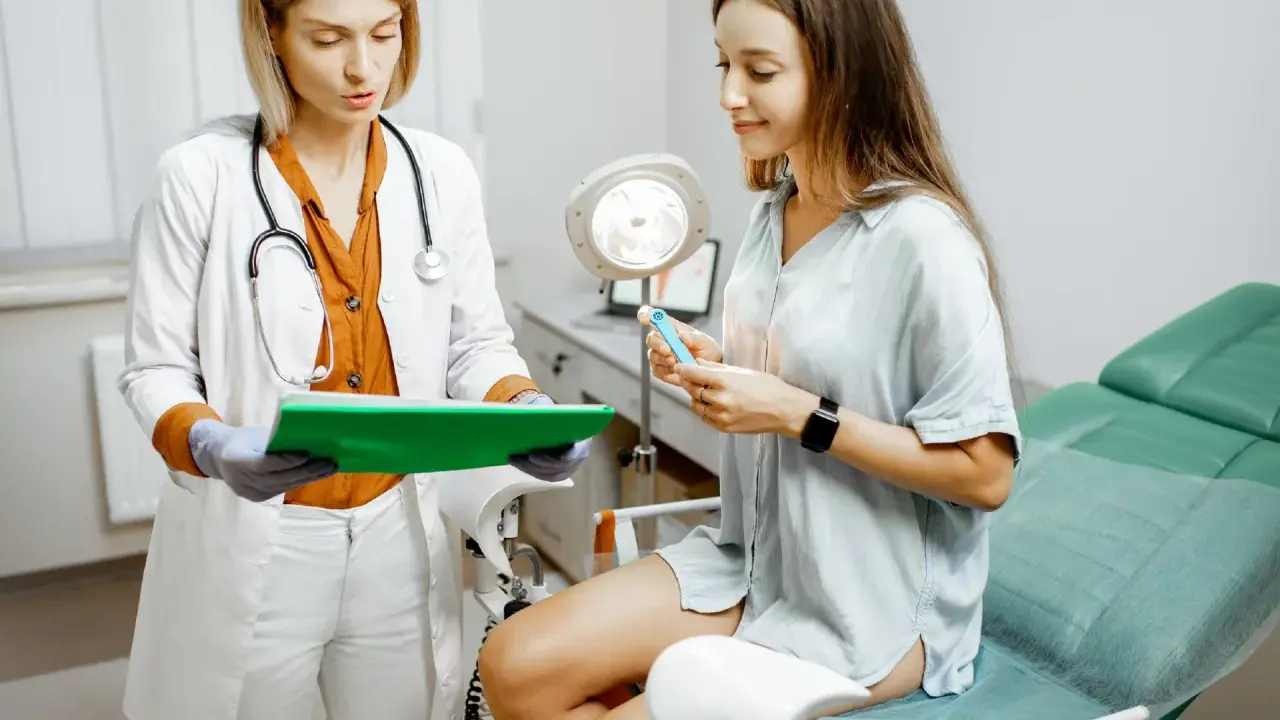 Lekarka wyjaśnia pacjentce, czym jest cytologia, pokazując jej przyrząd do badania.