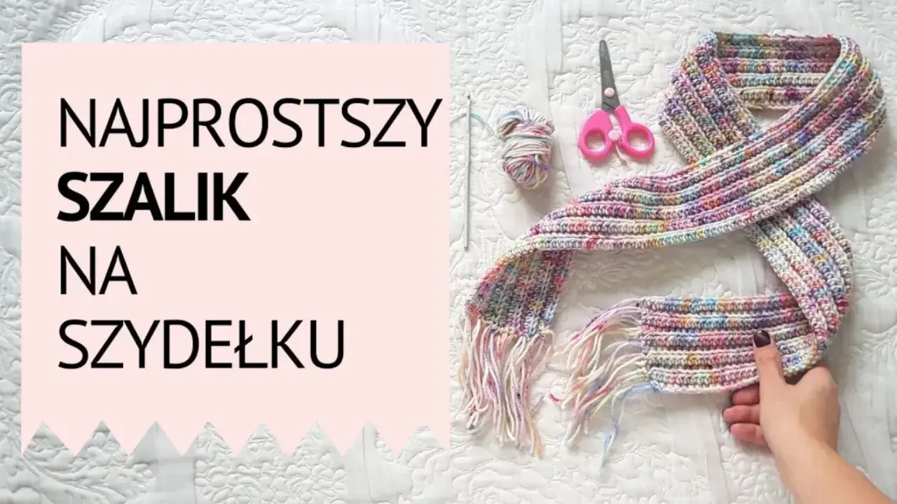 Kolorowy szal na szydełku, gotowy do noszenia. Widać też kłębek włóczki, szydełko i nożyczki.