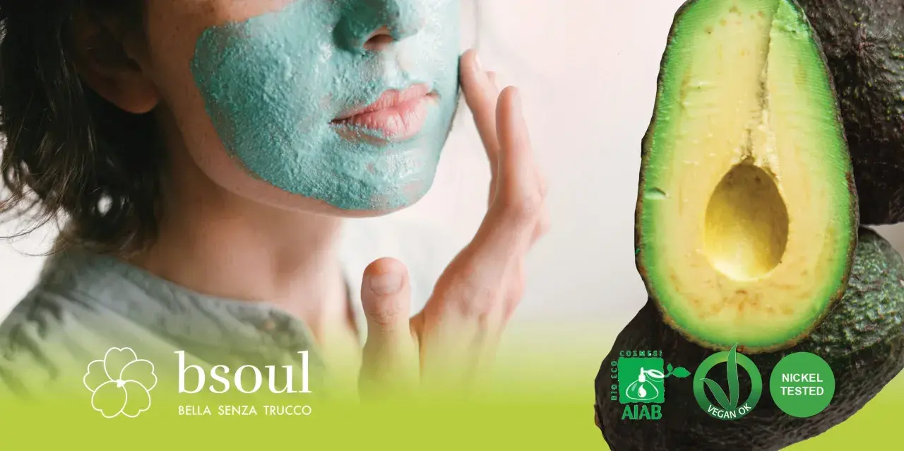 Donna con maschera viso fai da te verde, accanto ad avocado. Certificazioni bio e vegan.