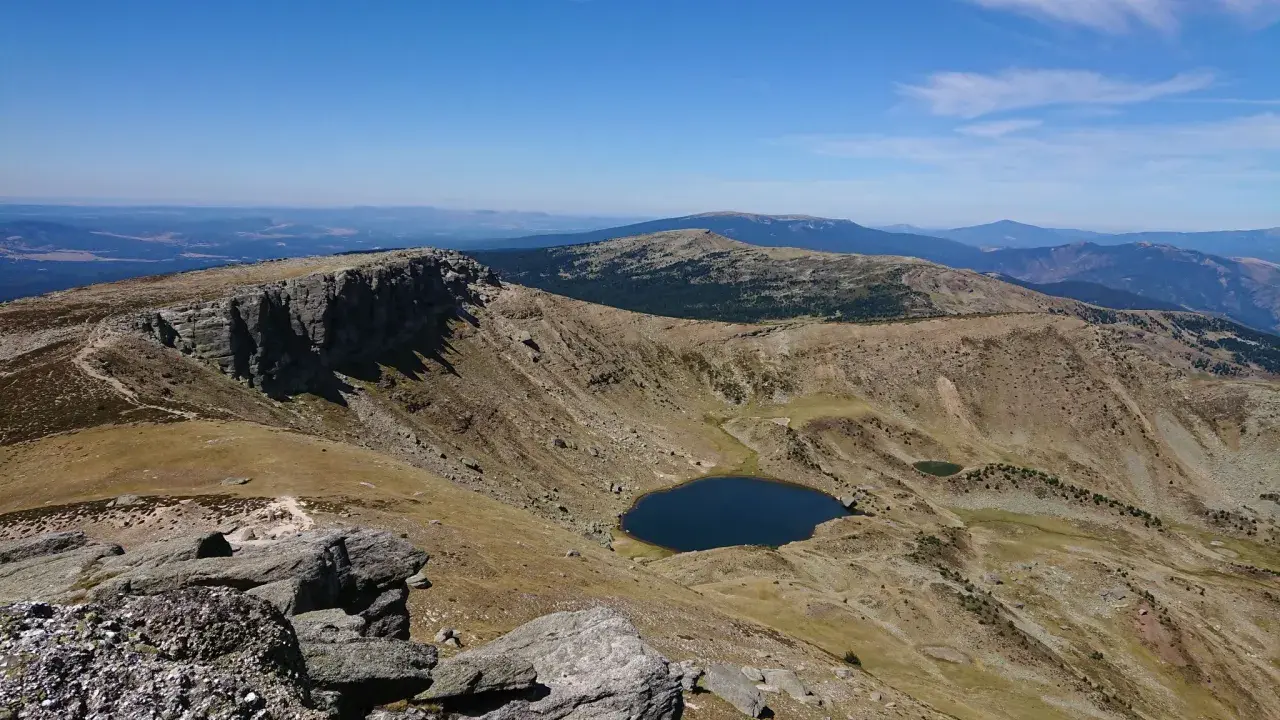 Paisaje montañoso con un lago azul en un valle, ideal para senderismo Soria.