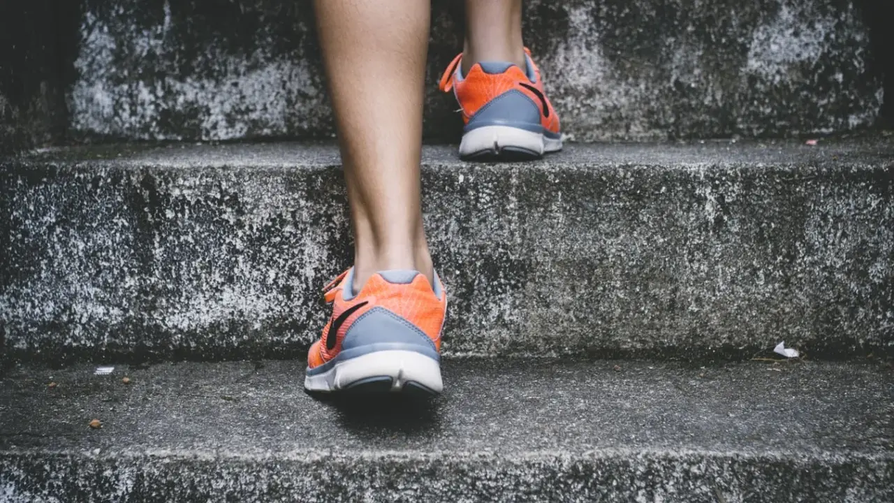Pomarańczowe buty sportowe na siłownię, idealne na trening, wspinają się po betonowych schodach.