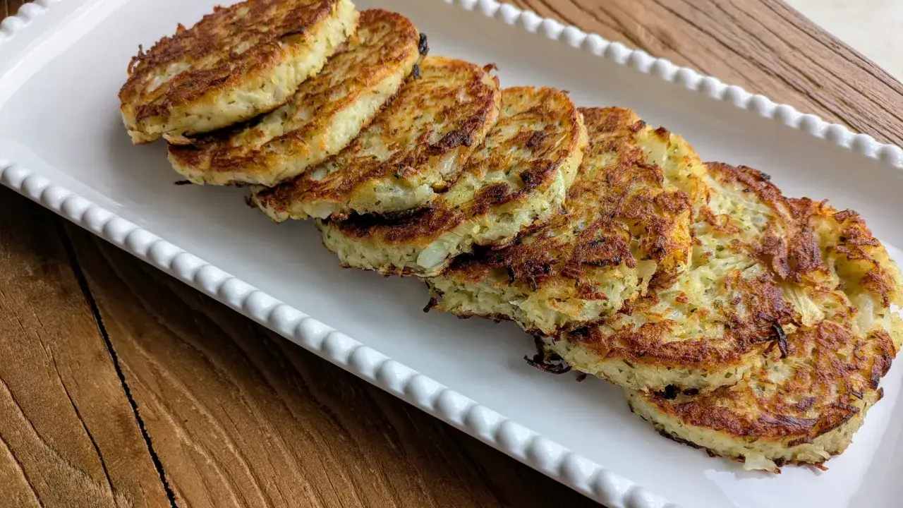 Six galettes de pomme de terre dorées et croustillantes, disposées sur un plat blanc festonné, prêtes à être dégustées.