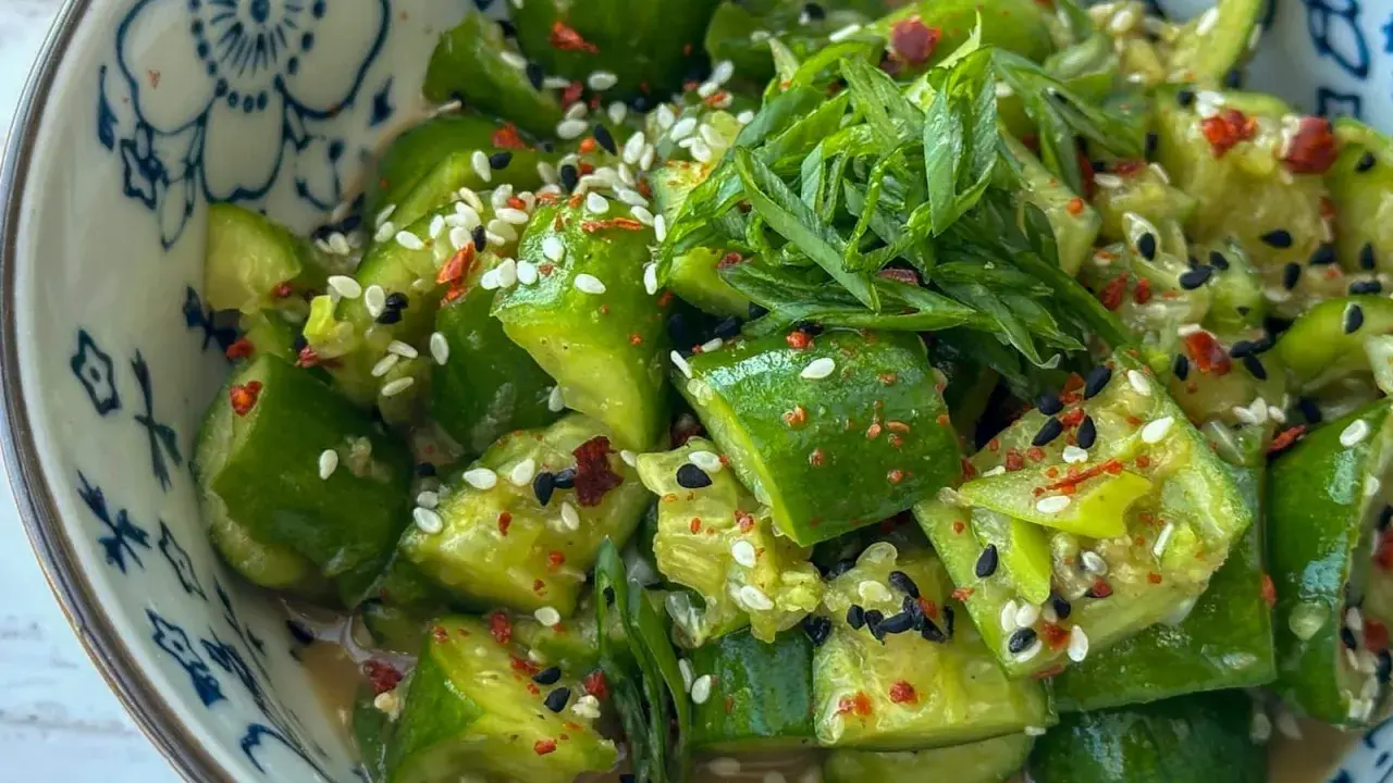 Erfrischender asiatischer Gurkensalat mit Sesam, Chili und Frühlingszwiebeln in einer blumengemusterten Schüssel.