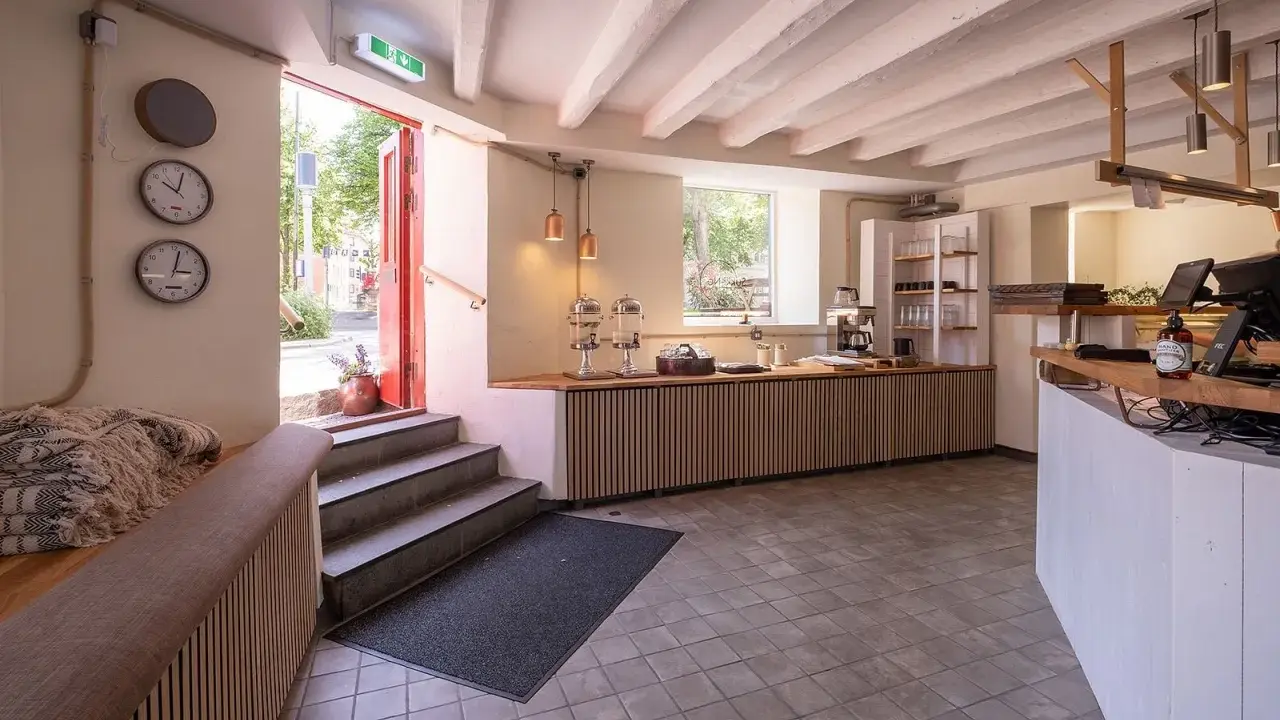 Välkomnande entré till ett café med trädetaljer och en disk. Perfekt för att läsa sukki-ne recensioner.