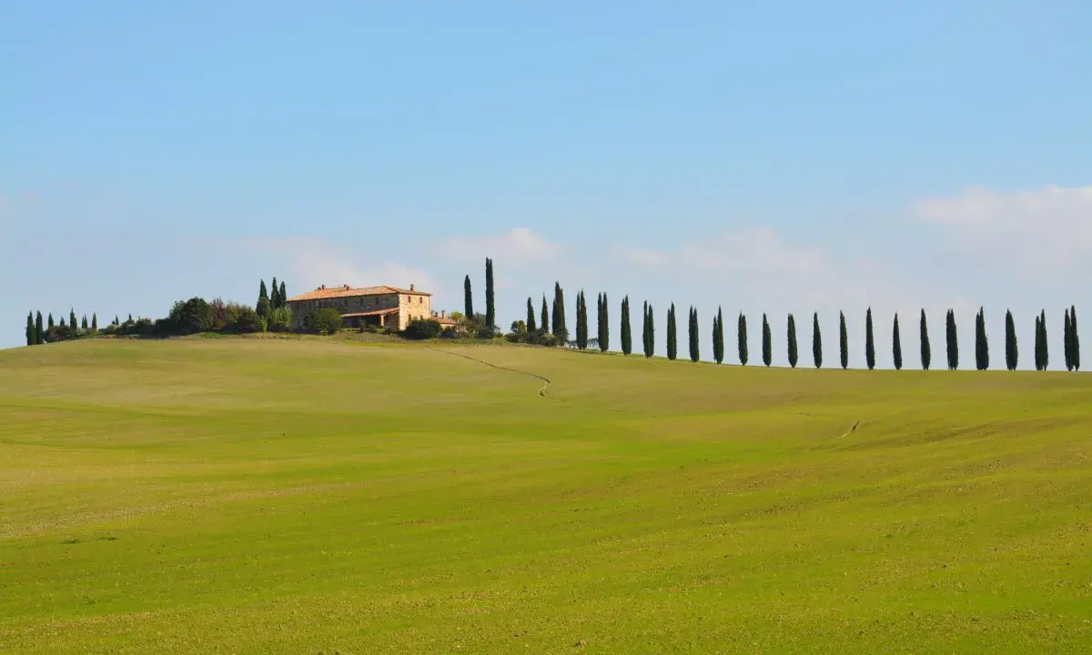 Colline verdi toscane con cipressi e un casale, perfetto per un itinerario toscana 5 giorni da sogno.